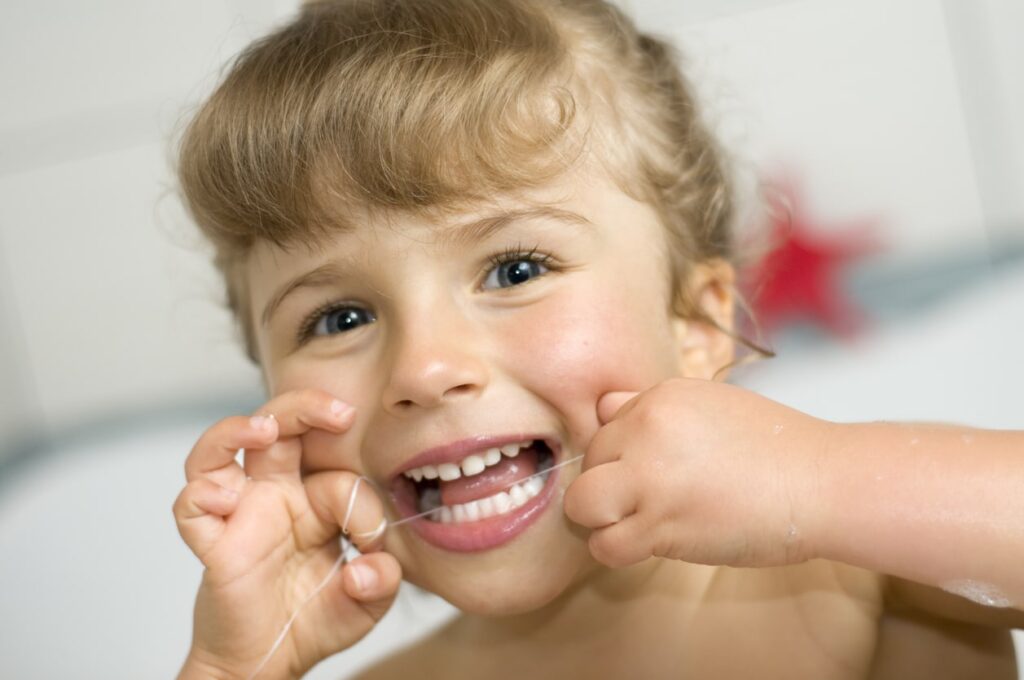 a photo of a little girl showing everyone how to floss