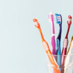 Cup Of Colorful Toothbrushes On A Pale Blue Background