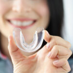 Smiling Woman Holds Transparent Plastic Mouth Guard In Her Hand