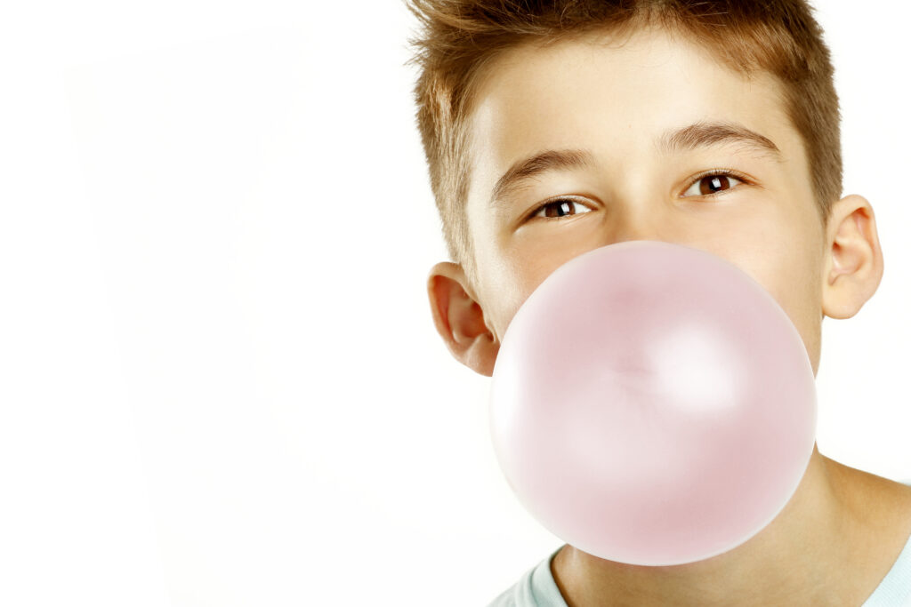 is chewing gum bad for you? this is a boy blowing a bubble with his mouth using bubble gum.