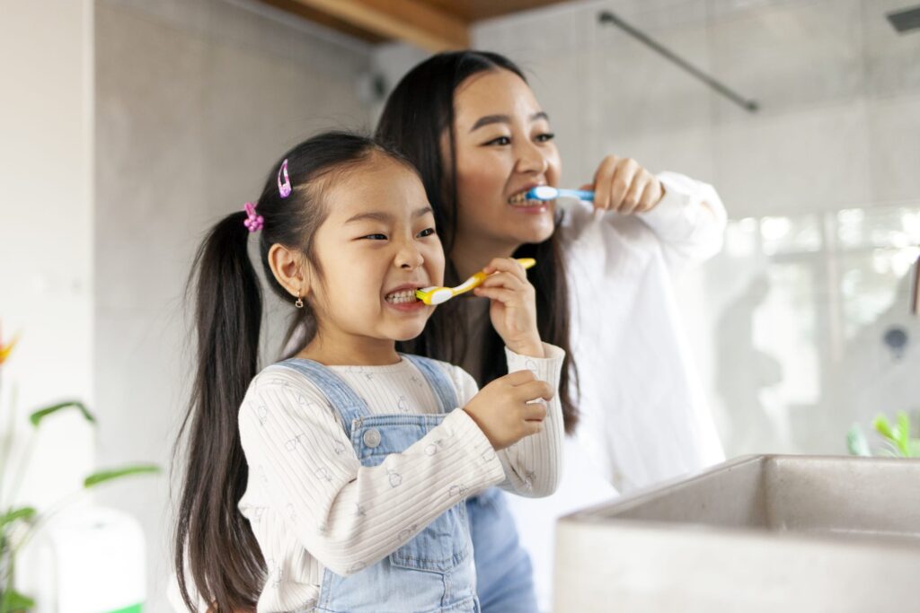 Mother and young daughter brushing their teeth together